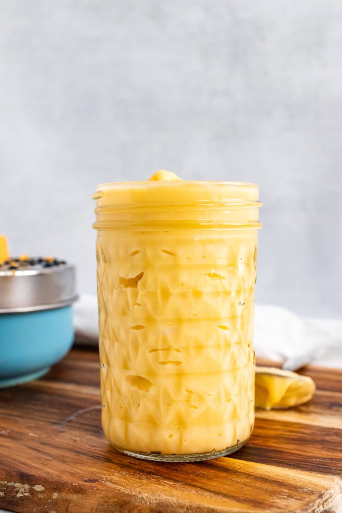 Homemade Condensed Cheddar Cheese Soup in a glass mason jar on a wooden cutting board