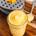 Homemade Condensed Cheddar Cheese Soup in a glass mason jar on a wooden cutting board