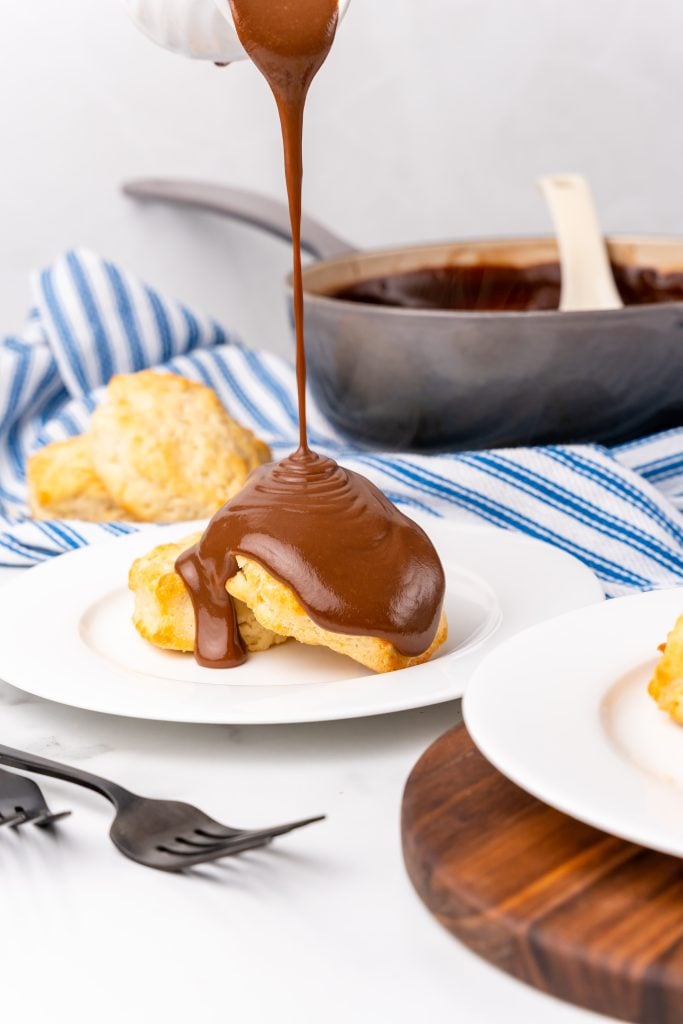 grandma's chocolate gravy recipe being ladled over biscuits on a white plate