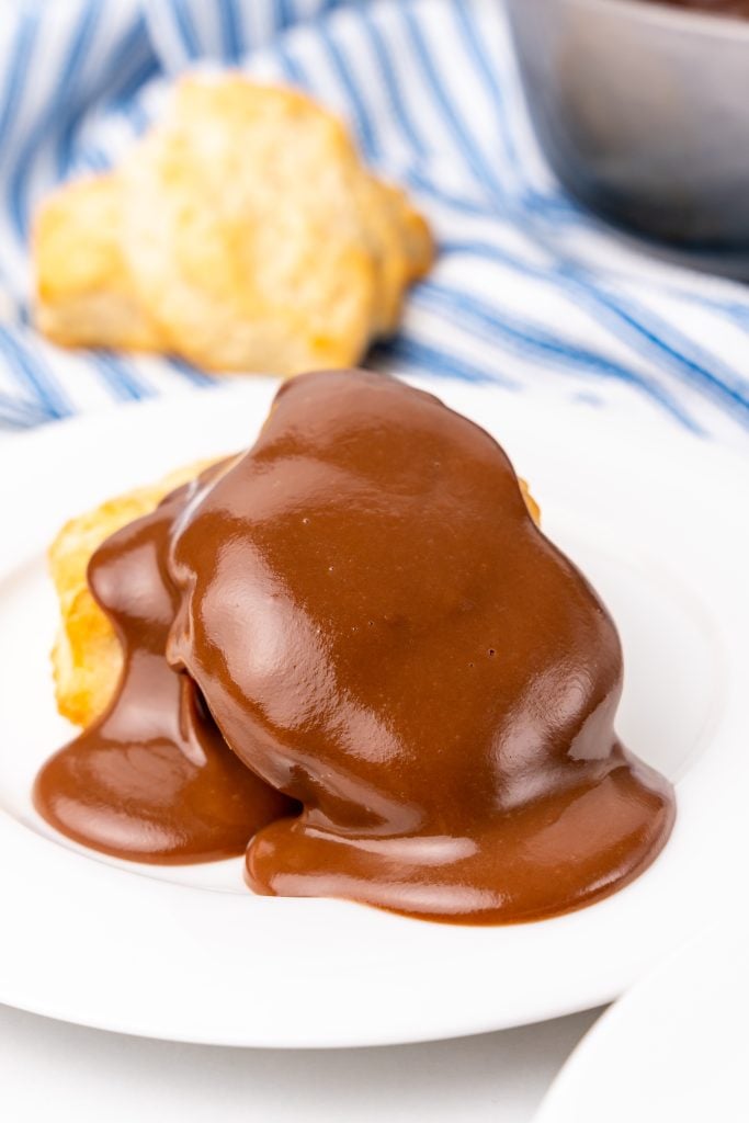 grandma's chocolate gravy poured over biscuits on a white plate