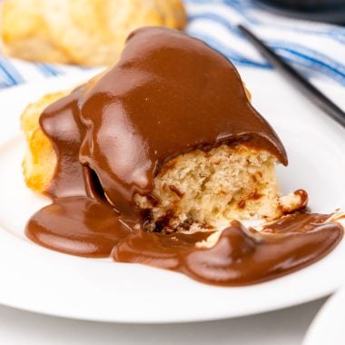 grandma's chocolate gravy recipe poured over biscuits on a white plate