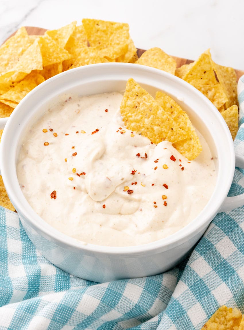 homemade mexican white sauce in a small white serving bowl with crispy tortilla chips on the side