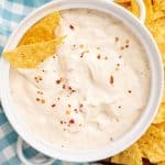 homemade mexican white sauce in a small white serving bowl with crispy tortilla chips on the side