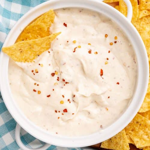 homemade mexican white sauce in a small white serving bowl with crispy tortilla chips on the side
