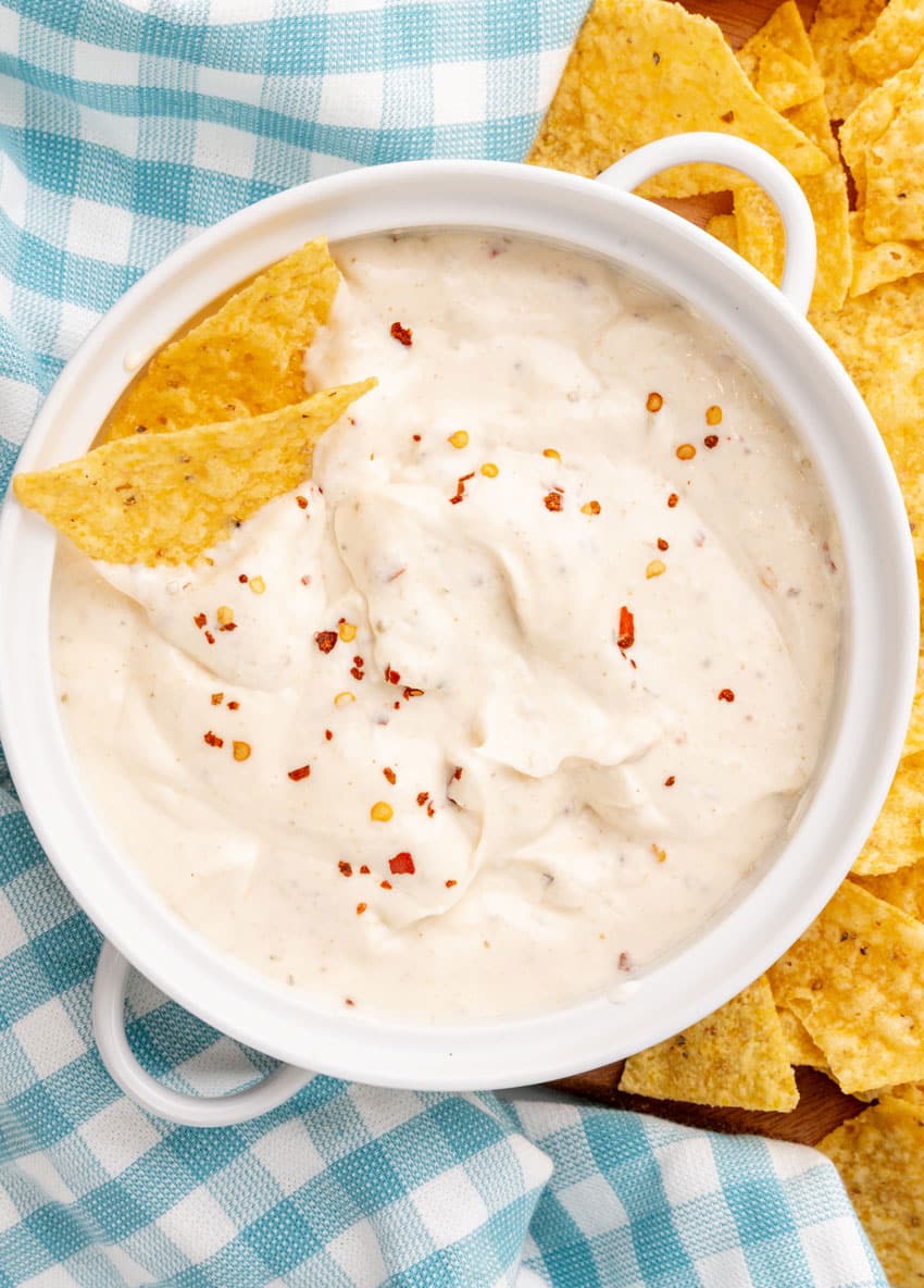 homemade mexican white sauce in a small white serving bowl with crispy tortilla chips on the side