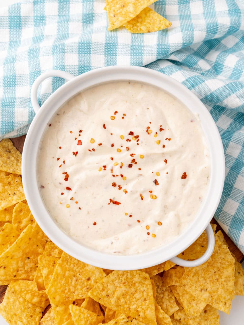 homemade mexican white sauce in a small white serving bowl with crispy tortilla chips on the side