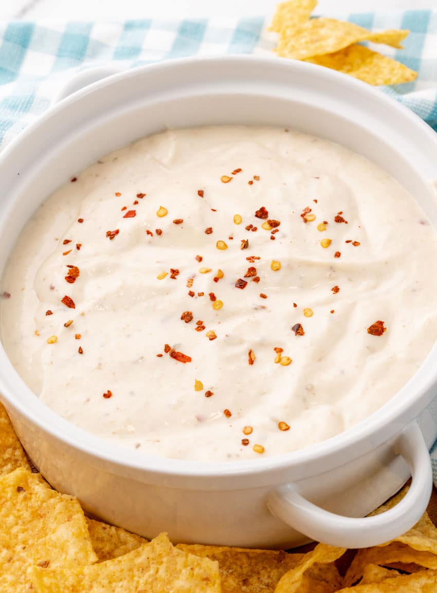 homemade mexican white sauce in a small white serving bowl with crispy tortilla chips on the side