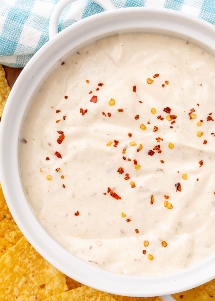 homemade mexican white sauce in a small white serving bowl with crispy tortilla chips on the side