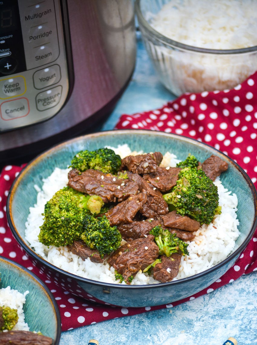 Instant pot beef and broccoli over white rice in a green bowl
