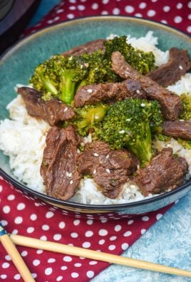 instant pot beef and broccoli in a green bowl next to a pair of wooden chopsticks