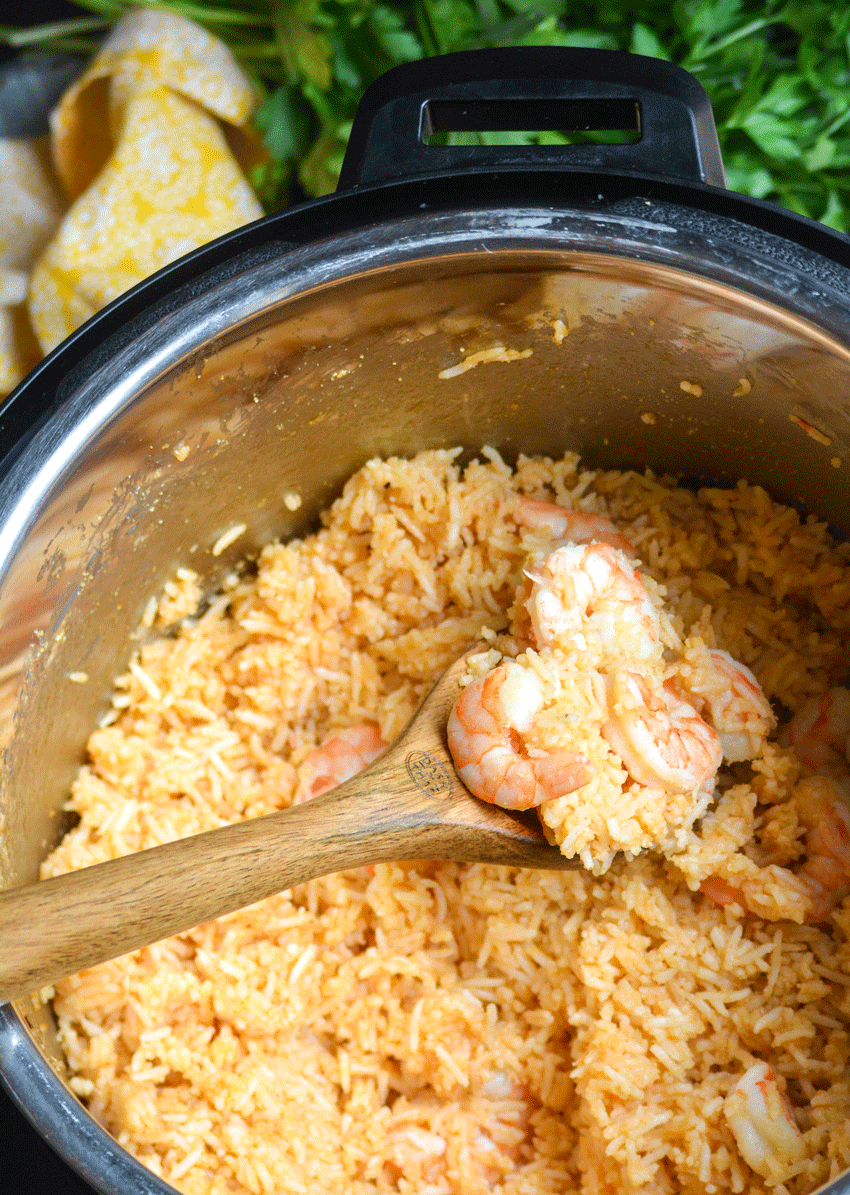 fluffy shrimp and rice with sweet and sour sauce in an instant pot with a wooden spoon