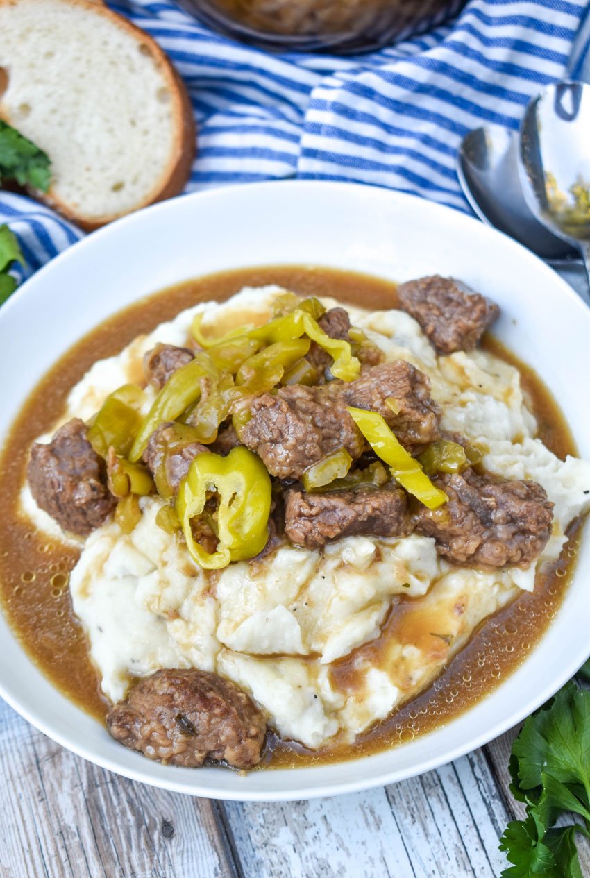 mississippi beef stew served over mashed potatoes in a white bowl