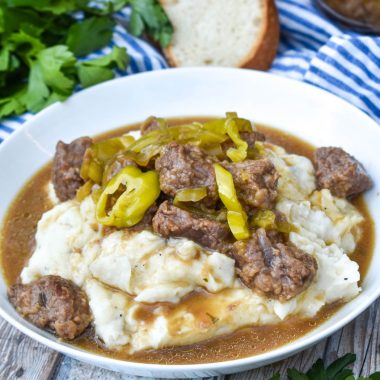 mississippi pot roast served over mashed potatoes in a white bowl