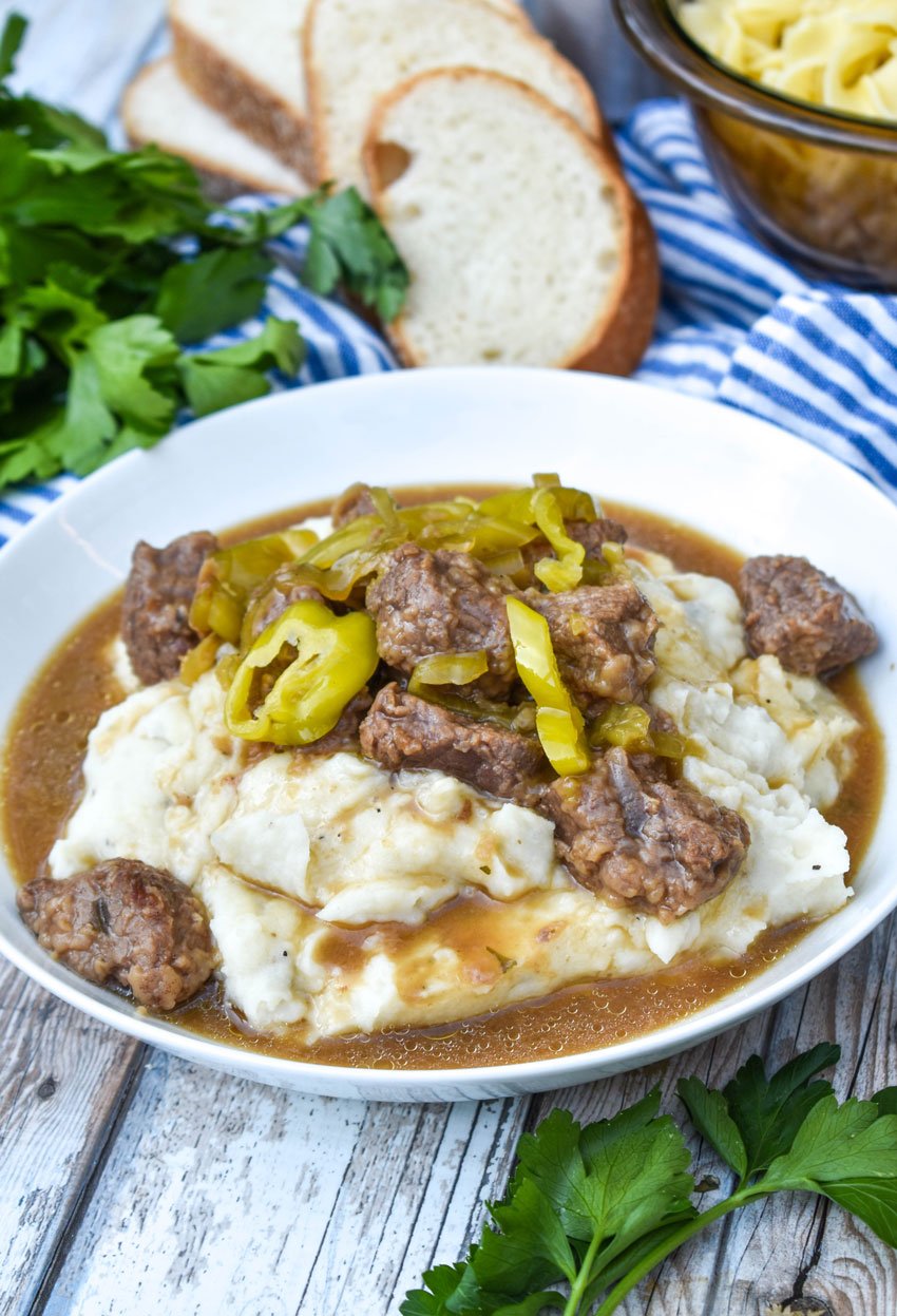 mississippi pot roast served over mashed potatoes in a white bowl