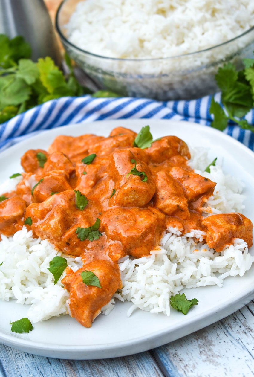 slow cooker butter chicken over a bed of steamed white rice on a white plate