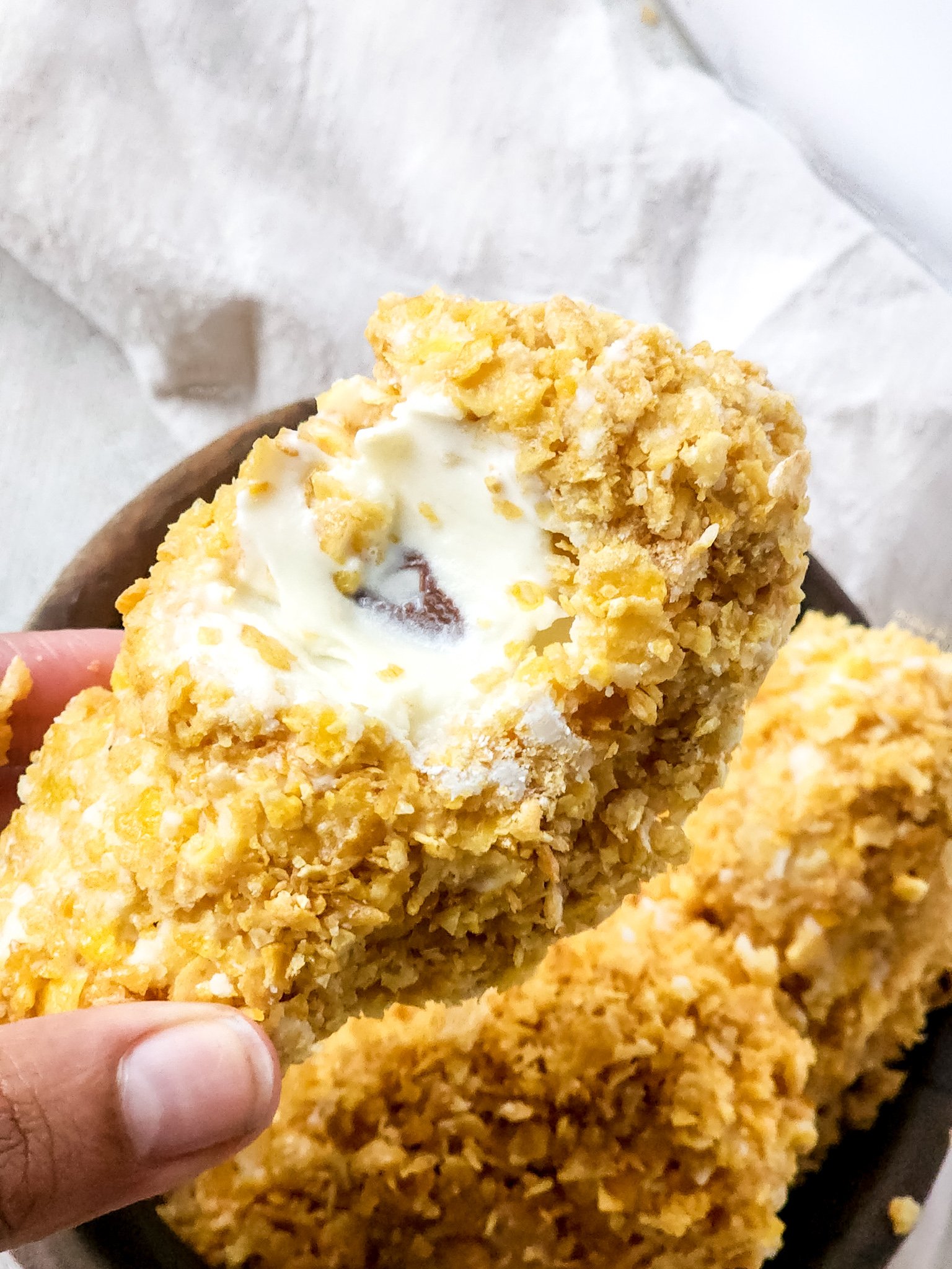 a hand holding up a piece of fried chicken ice cream