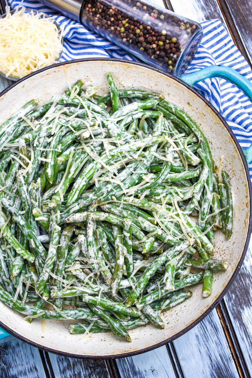 creamy caesar green beans in a blue cast iron skillet