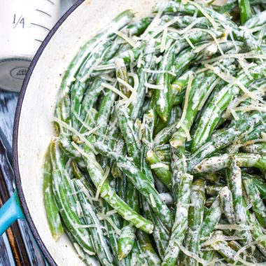creamy caesar green beans in a blue cast iron skillet
