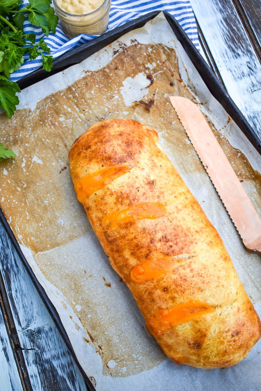a baked ham and cheese stromboli on a parchment paper lined baking sheet