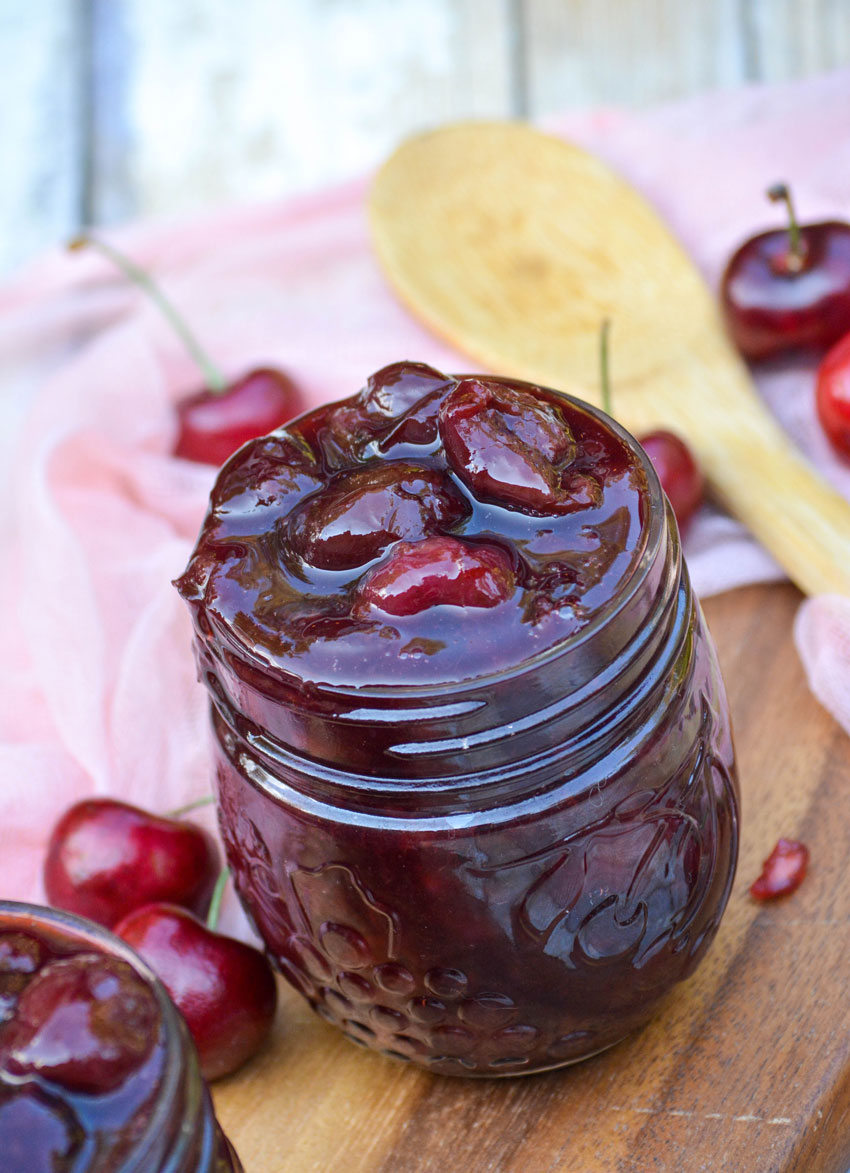 instant pot cherry pie filling in a small glass jar on a wooden cutting board