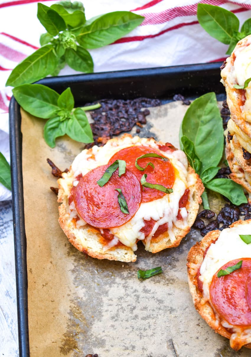 english muffin pizzas on a parchment paper lined baking sheet