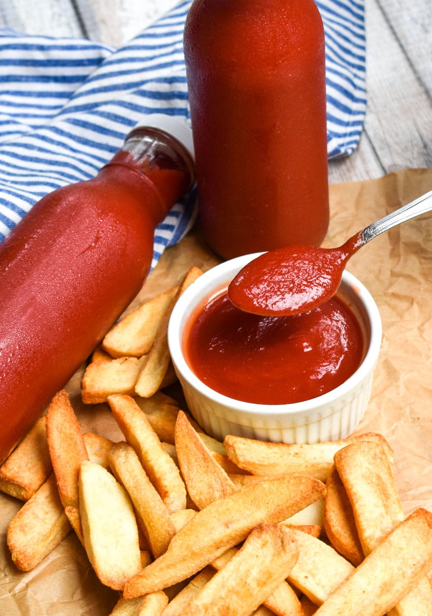 a silver spoon holding up a scoop of slow cooker ketchup