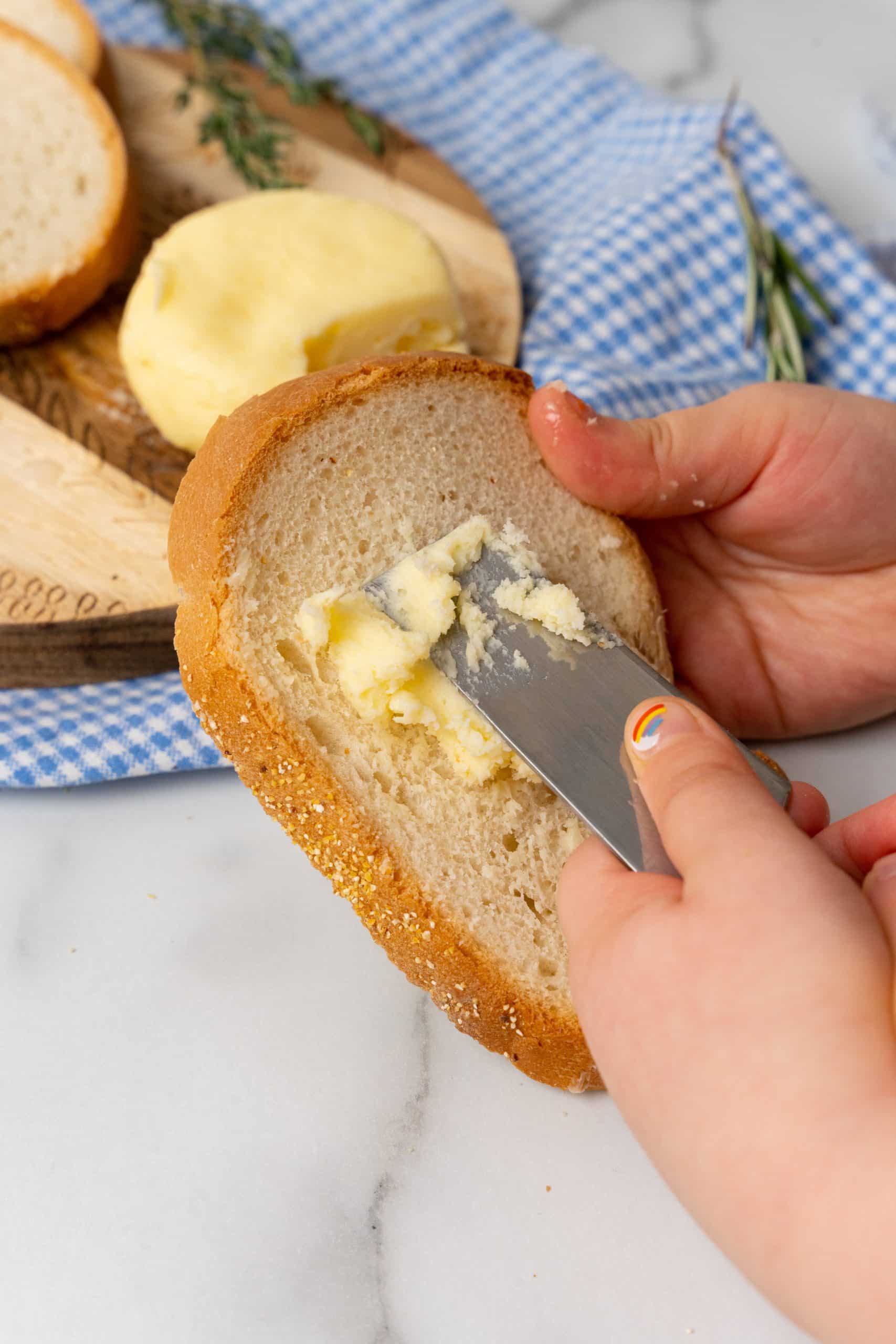 small hands spreading fresh homemade butter on a slice of bread