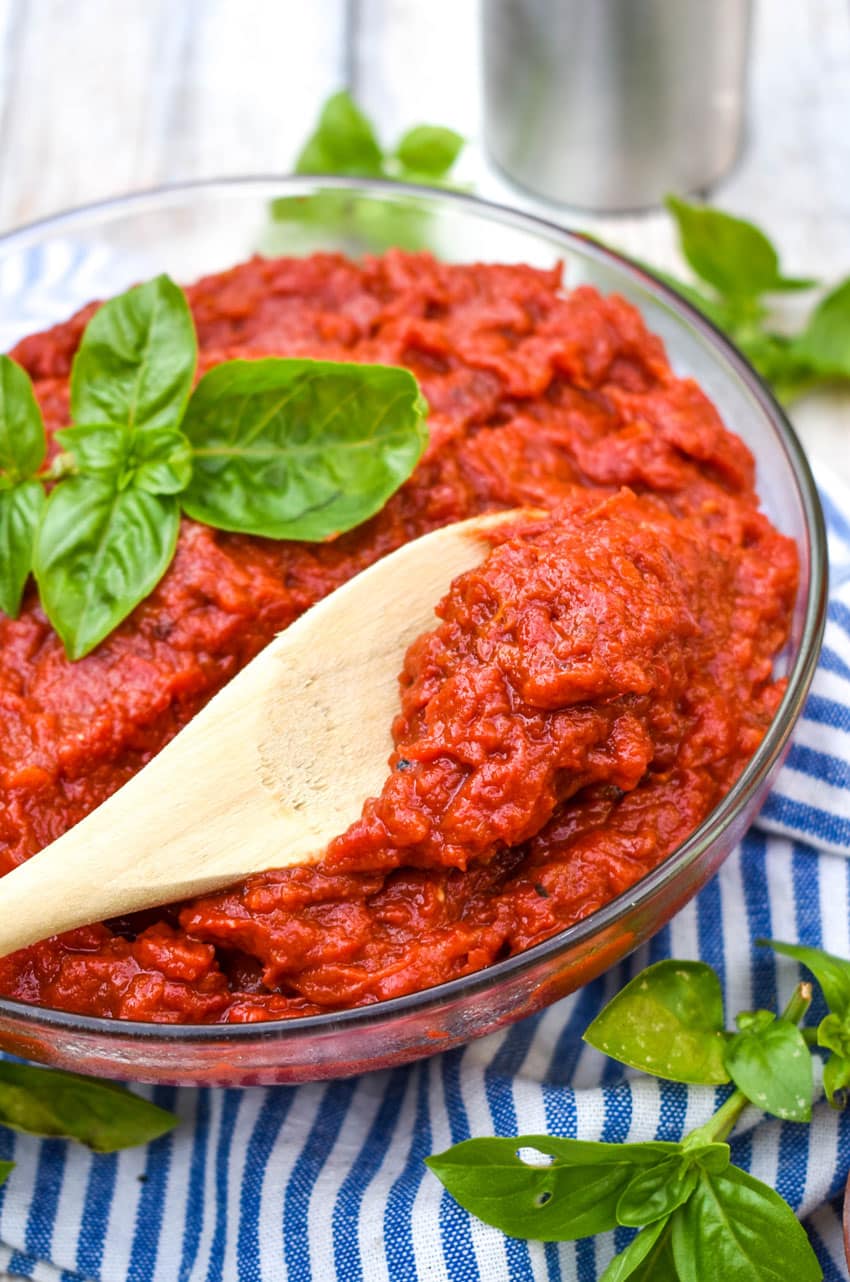 a wooden spoon in a glass bowl of easy tomato paste recipe