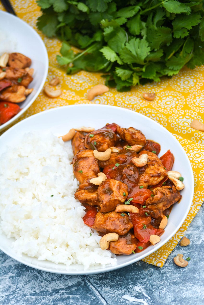 kung pao chicken on a white plate with steamed white rice on the side
