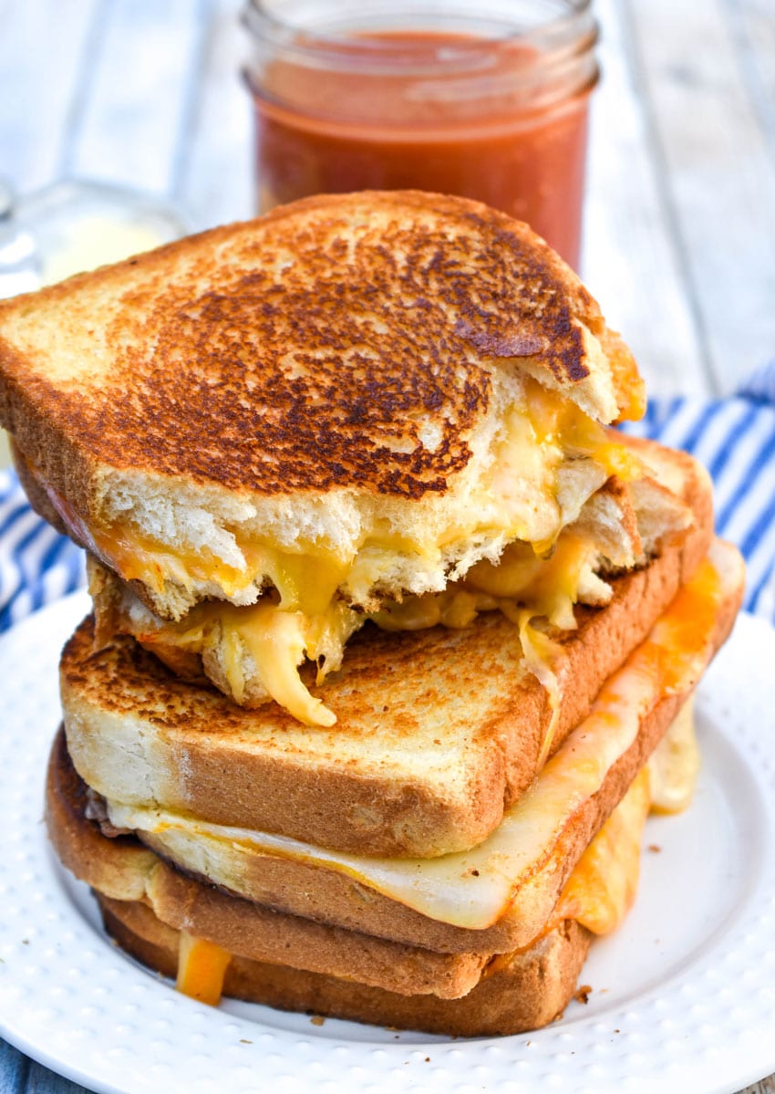 the best grilled cheese sandwiches stacked on a white plate