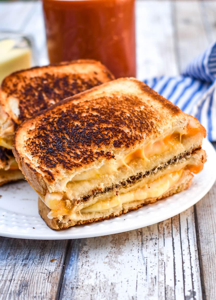 the best grilled cheese sandwich cut in half and served on a white plate