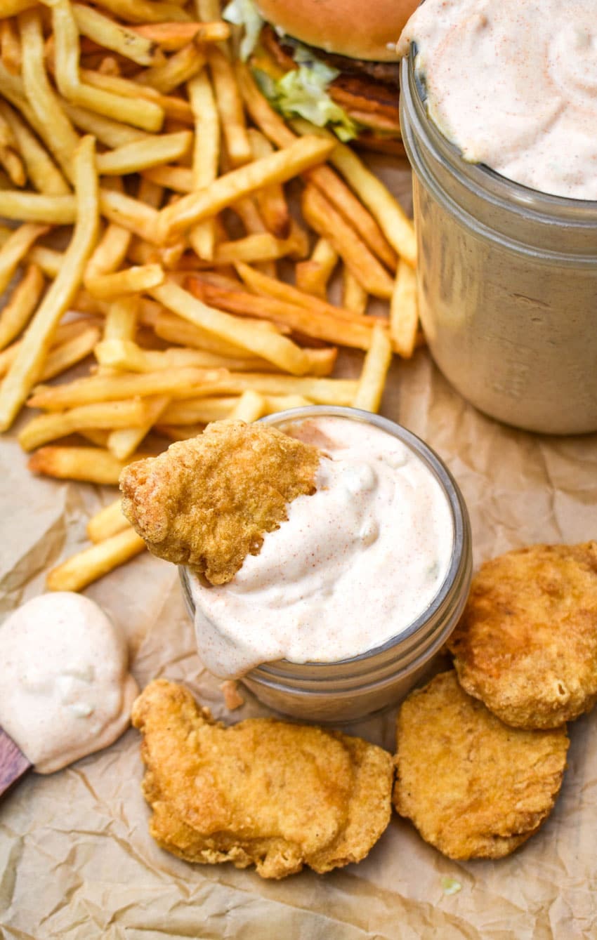 a chicken nugget resting in a glass jar filled with copycat big mac sauce