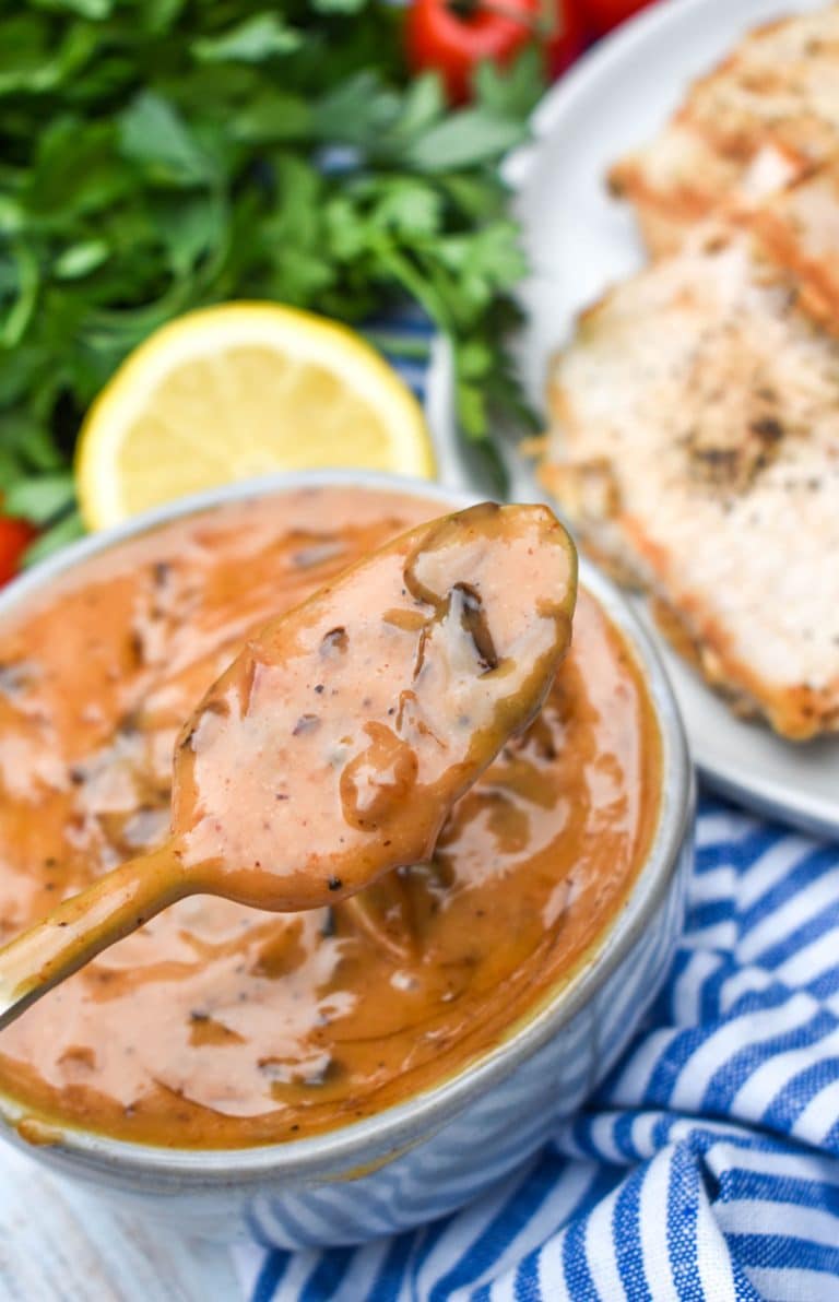 a silver spoon holding up a scoop of Taziki's tomato chutney above a small gray bowl