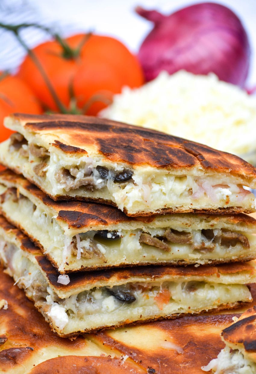 slices of greek gyro quesadillas stacked on a wooden cutting board