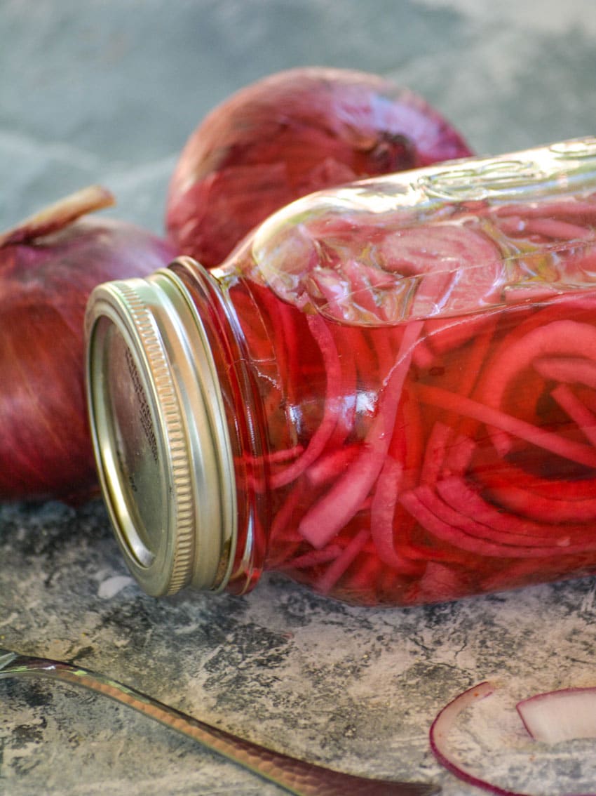 quick pickled onions in a large glass jar resting on its side