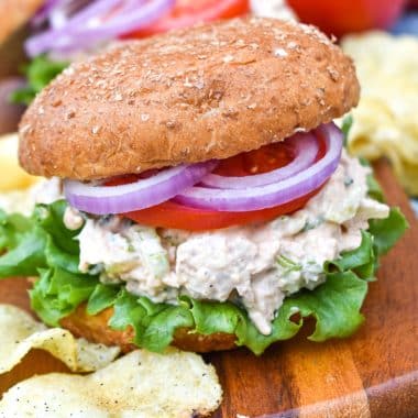 smoked chicken salad on a fluffy wheat bun sitting on a wooden cutting board