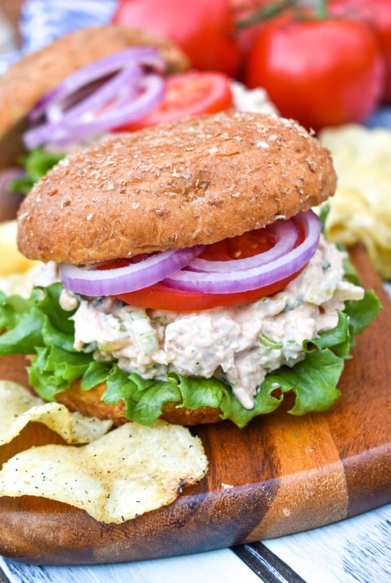 smoked chicken salad on a fluffy wheat bun sitting on a wooden cutting board