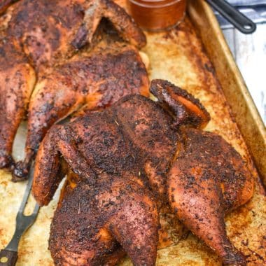 two smoked spatchcock chickens on a metal sheet pan