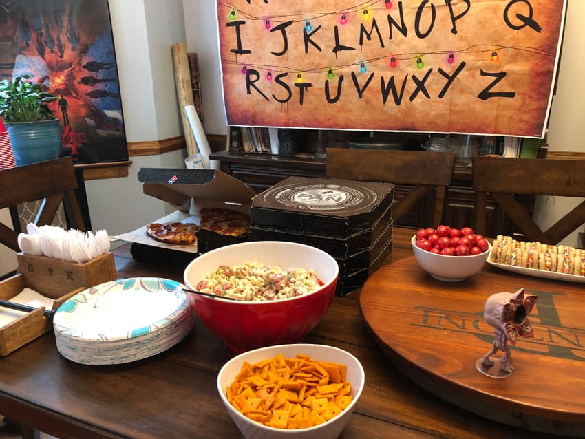 stacked pizzas and macaroni salad served on a wooden kitchen table