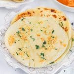 slices of air fryer garlic naan bread piled on a white plate