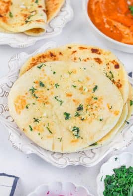slices of air fryer garlic naan bread piled on a white plate