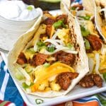 a row of breakfast tacos arranged on a white serving platter