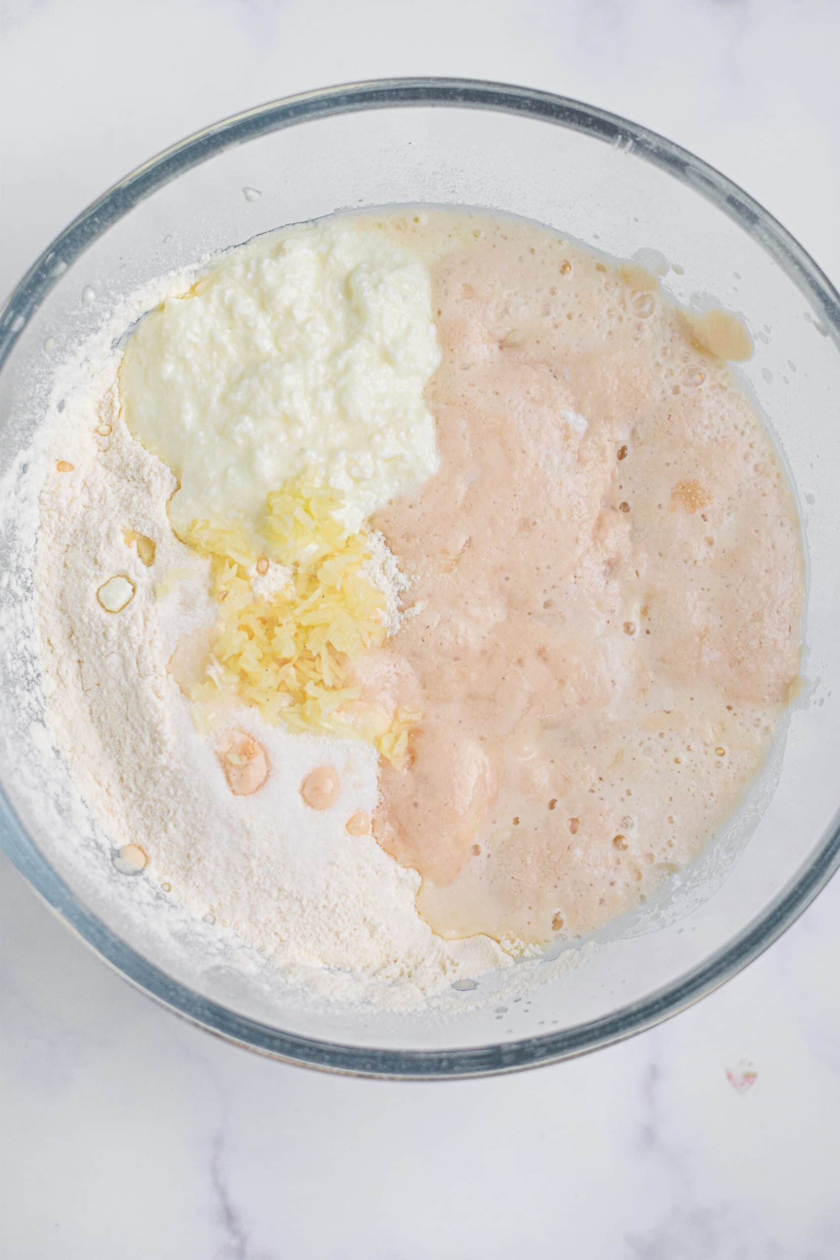 ingredients for bread dough in a glass mixing bowl