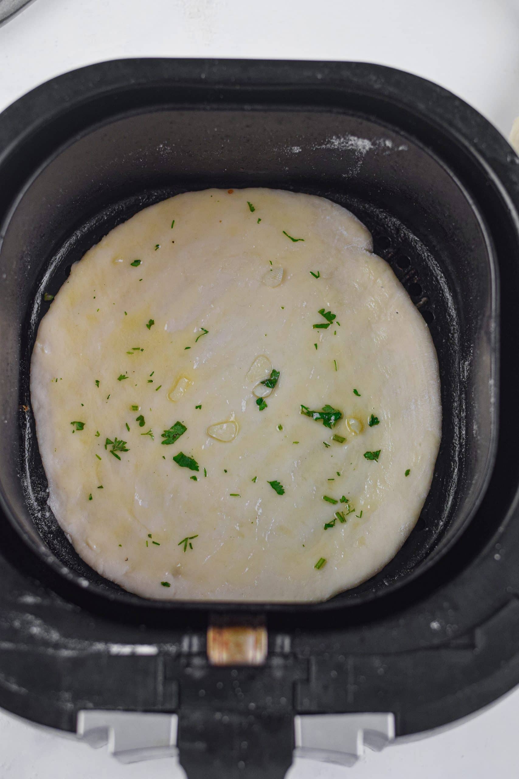 garlic buttered naan bread in the basket of an air fryer
