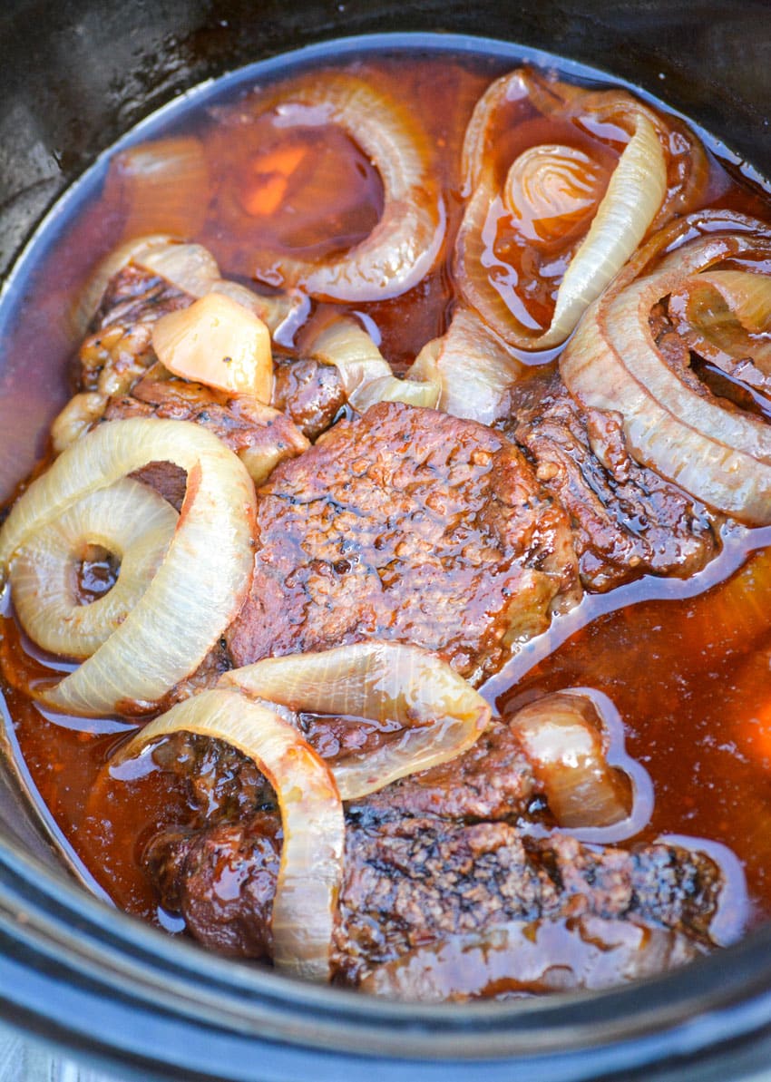 balsamic pot roast with onions in the black bowl of a crockpot