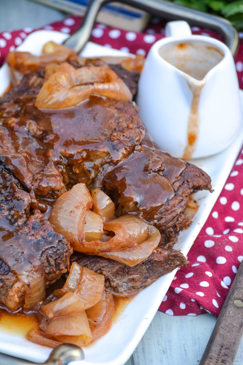 balsamic pot roast with onions on a white platter topped with gravy