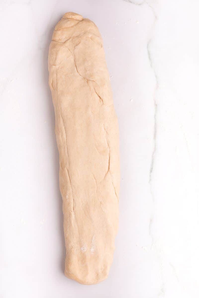 dough stretched out into a roughly 18 inch long rectangle on a floured countertop