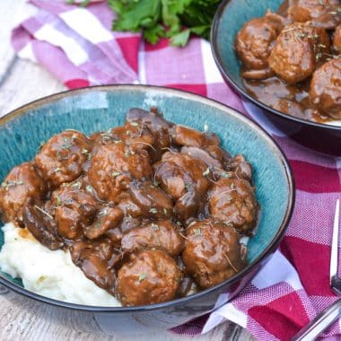 meatballs in mushroom gravy over mashed potatoes in a blue bowl