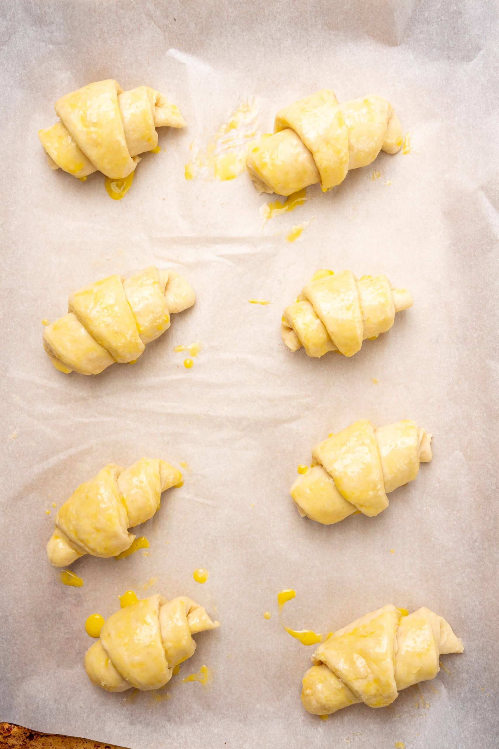 unbaked croissant rolls on a parchment paper lined baking sheet