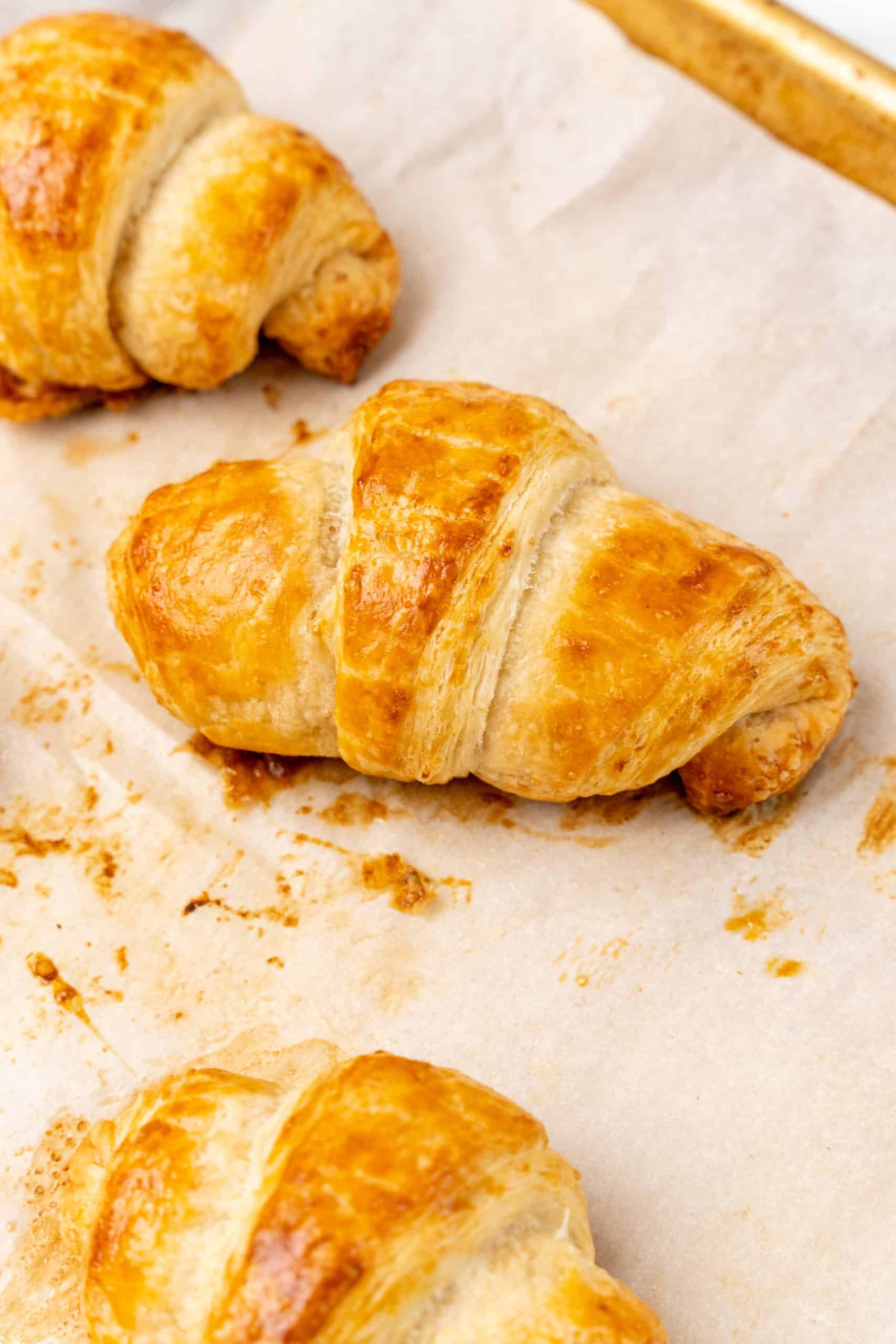 freshly baked homemade croissants on a parchment paper lined baking sheet